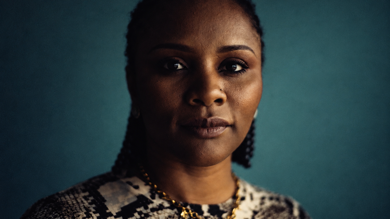 Portrait de la cinéaste haïtienne Gessica Généus, réalisatrice de « Marie Madeleine », sur un fond bleu sombre.