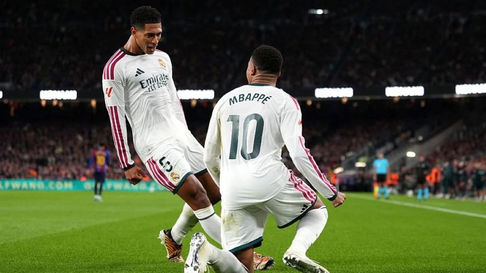 Kylian Mbappé, à genoux sur la pelouse, célèbre son but avec Jude Bellingham lors du Clásico entre le Real Madrid et le FC Barcelone.